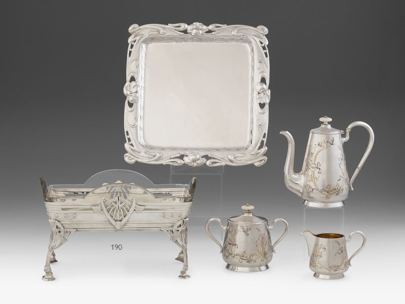 190. tétel, Német jugendstil jardiniere    Ezüst, 500 g. Négy lábon álló téglalap formájú edény. Felületén áttört, domborított geometrikus díszítmény, sarkain szecessziós tulipáncsokrok. Fúvott és csiszolt, eredeti üvegbetétjén csorbult.     Jelzett: Schw