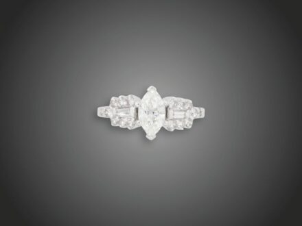 166. tétel, Női gyűrű  Fehérarany 585, karmos foglalatban 1 navett csiszolású briliáns cca. 1,0 ct (MTCVs1), gyűrűvállakon 2 baguett csiszolású és 16 kis kerek csiszolású briliáns cca. 0,80 ct (MTCrVs) ékítéssel, 4,6 g, átmérő: 17,3 mm