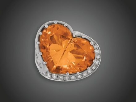 111. tétel, Női gyűrű  Fehérarany 750, egyedi tervezésű, 1 nagy karmos foglalású, szívformára csiszolt citrin cca. 25,0 ct, természetes zárványokkal, 22 kisebb-nagyobb briliáns cca. 1,60 ct (MWVs) ékítéssel, 28,8 g, átmérő: 17,0 mm, tanúsítvánnyal, dobozz