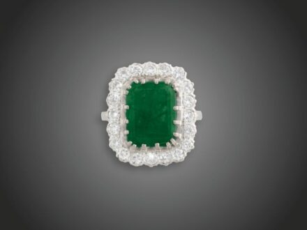 53. tétel, Női gyűrű  Fehérarany 585, karmos foglalású nagyobb smaragd cca. 5,0 ct természetes zárványokkal, körülötte 20 briliáns cca. 1,40 ct (MCrSi) karmazált fazonban, 8,9 g, átmérő: 18,0 mm