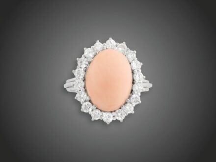 51. tétel, Női gyűrű  Fehérarany 750, karmos foglalatban 1 kaboson csiszolású rózsa korall és 18 briliáns cca. 1,20 ct (MTCrSi) karmazált fazonban, 7,6 g, átmérő: 19,0mm