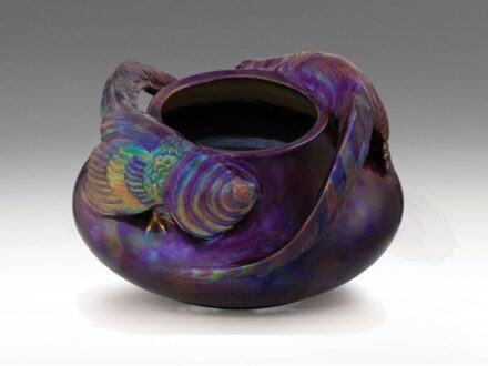 474. tétel, Zsolnay szecessziós virágtartó, fácánokkal  Fehércserép. Öntött forma, ráillesztett, megmintázott elemekkel. Felülete opak, fémszínű és színes eozinmázakkal-, az alap márványozott mintával festett. Savmaratott, tompa fényű. Szájperemén gyári t