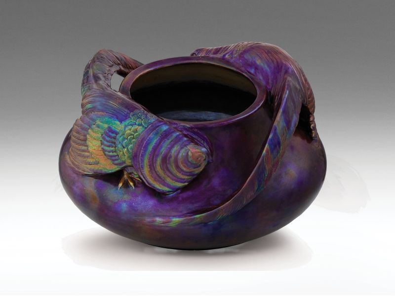 474. tétel, Zsolnay szecessziós virágtartó, fácánokkal  Fehércserép. Öntött forma, ráillesztett, megmintázott elemekkel. Felülete opak, fémszínű és színes eozinmázakkal-, az alap márványozott mintával festett. Savmaratott, tompa fényű. Szájperemén gyári t