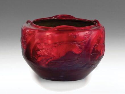 472. tétel, Zsolnay szecessziós virágtartó  Formába öntött porcelánfajansz. Plasztikus  elemekkel díszített, felületén kontúrrajzos,   ill. reliefszerű a laterna magica ötletén alapuló  jelenet: nyulat üldöző vadászkutyák.  Felületén színes eozinmázakkal