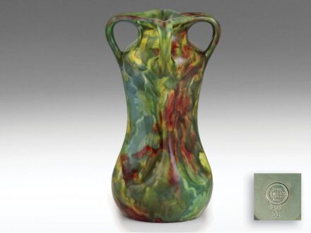 470. tétel, Zsolnay szecessziós díszváza  Fehércserép. Korongozott, kézzel alakított forma, kihajló szájperemén plasztikus fülekkel.  Felületén többszínű, lefolyó, magas tűzön égetett majolikamázakkal.  Formaterv: Sikorski Tádé, 1900.  Forma: 9. Facon-kön