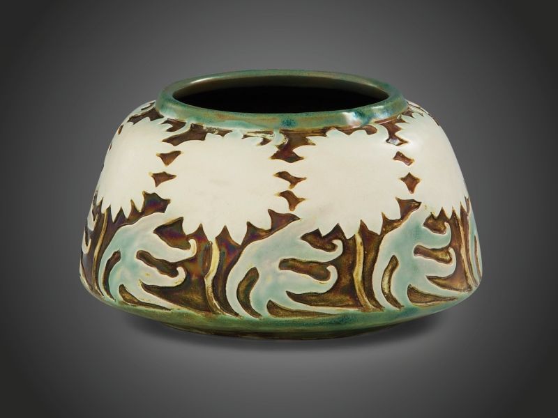 468. tétel, Zsolnay szecessziós váza  Formába préselt fehércserép, oldalán krizantémos frízzel. Felületén selymesfényű, színes és matt eozinmázakkal festett, részben savmaratott.   Forma-és dekorterv: feltehetően Apáti Abt Sándor.  Alján jelzett: masszába