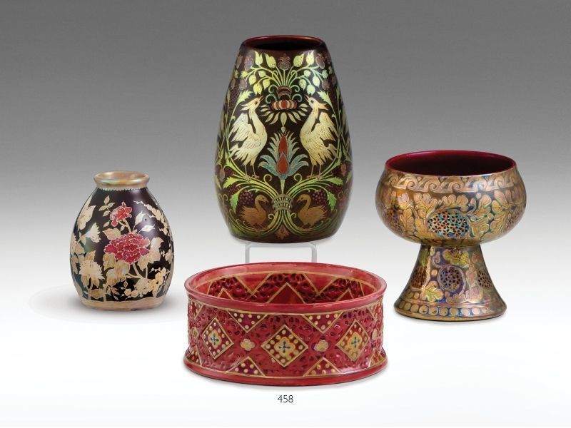 458. tétel, Zsolnay dísztálka   Formába öntött fehércserép. Áttört, geometrikus díszítésű oldalfalán, az azsúrzománcok hatását mintázó piros mázzal, öblében színes-, és fémfényű eozinmázakkal festett virágmotívum, ill. ún. millenniumi dekor. Szájperemén é