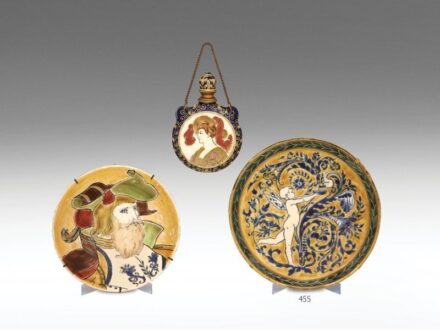 455. tétel, Zsolnay dísztányér   Porcelánfajansz. Elefántcsontszín alapon magas tüzű, okkersárga háttéren kobaltkékkel festett romantikus jelenet: stilizált hattyút itató lepkeszárnyas puttó.  Tányér alján a belső peremen apró csorba.  Dekorterv: Klein Ár