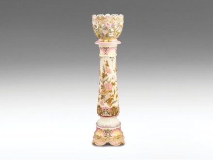 444. tétel, Zsolnay virágcseréptartó díszedény, állvánnyal  Domborműves formába préselt porcelánfajansz.   A virágtartó áttört falán magas tüzű, színes mázakkal festett és aranyozott virágmotívumok, ill. peremein plasztikus legyezőkagylós elemek. Hajszálr