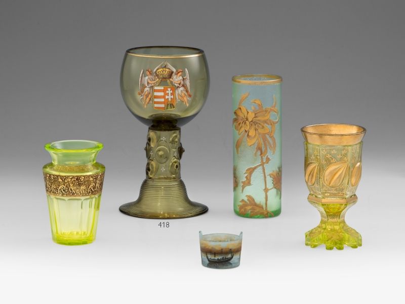 418. tétel, Díszpohár  Röhmer vagy rajnai borospohár típusú, fúvott sötétzöld hutaüveg, aranyozva. Palástján pasztózus zománcfestéssel Magyarország címere.  Szájperemén belül apró csorbák.  Cseh, 1900 körül.  M.: 20 cm