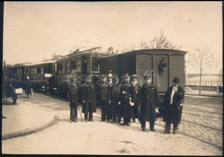 cca 1920-30 Vasutasok vagy HÉV-alkalmazottak csoportképe civilekkel a szentendrei HÉV járata előtt Budapesten, háttérben a Margit híddal. Jelzés nélküli fotó, kissé kopott 11,5x16,5 cm