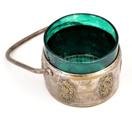 Ezüstözött alpakka kis méretű füles kínáló, domborműves díszítéssel, festett zöld üvegbetéttel. Jelzett, kopott, d: 7 cm, m: 6 cm