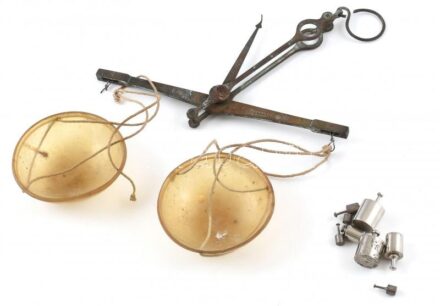 Régi kézi patikai mérleg, fém és műanyag, jelzett (Pinezits I. Bp., 1939 körül), hozzá 8 db súly gyógyszeres dobozban. Korának megfelelő állapotban, az egyik akasztója sérült.