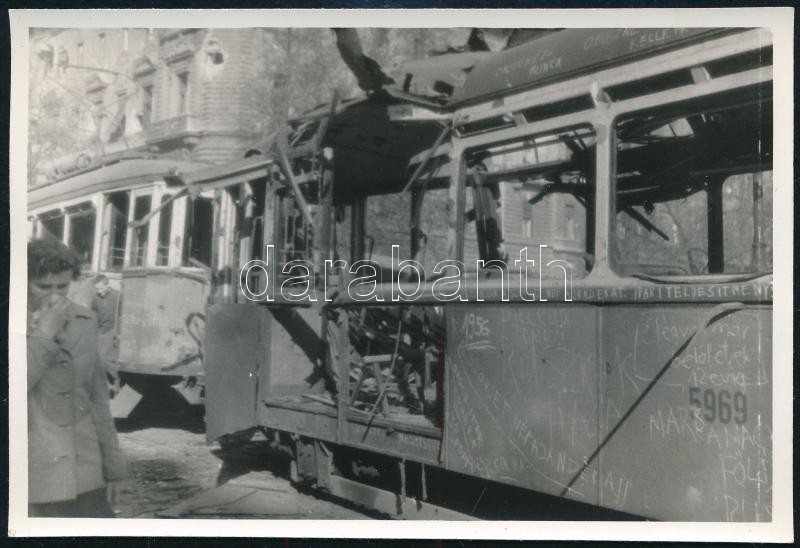 1956 Budapest, a harcok során kilőtt villamos a pesti utcán, oldalán érdekes feliratokkal, pl. 'köszönjük a szovjet nép ajándékát', fotó szép állapotban, 8×12,5 cm
