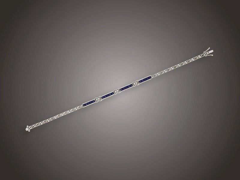 Karkötő
Fehérarany 750, keskeny tagokból, 4 tagon 20 szögletes
csiszolású zafír cca. 1,75 ct és 6 apró briliáns cca. 0,04
ct (MCrP1) ékítéssel, 8,4 g, hossz: 18,5 cm