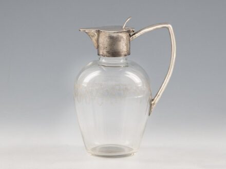 Karaffa_x000D_
Fúvott, színtelen üveg köszörült díszítéssel, ezüst füllel és billenőfedéllel._x000D_
Jelzett: Bécs, 1910 körül, Lippa & Co._x000D_
M.: 18 cm