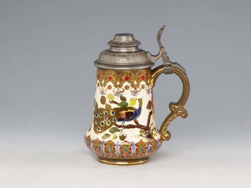 Historizáló díszkupa_x000D_
Színes mázakkal festett porcelánfajansz ón billenőfedéllel._x000D_
Alján jelzett: masszába nyomott Fischer I. Budapest, valamint máz alatti kékkel bélyegzett márkajelzéssel, ill. töredékes_x000D_
etikettcímke._x000D_
Fischer Ig