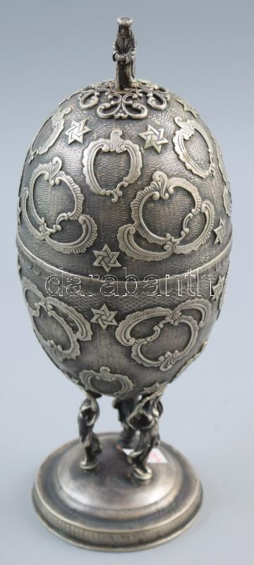 Ezüst (Ag) szukkoti etrogtartó. Orosz, 1891, 84 zolotnik, talapzaton három nőalak által tartott tojás, tetején Mózest figuráló fogóval benne belső zárófedélen a kőtáblák és Mózes ábrázolásával. Jelzett, m: 27,5 cm, 653g  Silver (Ag) Sukkot etrog holder. Russian, 1891, 84 zolotniks, egg held by three female figures on pedestal, with a tong depicting Moses on top, and an inner lid depicting the stone tablets and Moses. Marked, h: 27.5 cm,