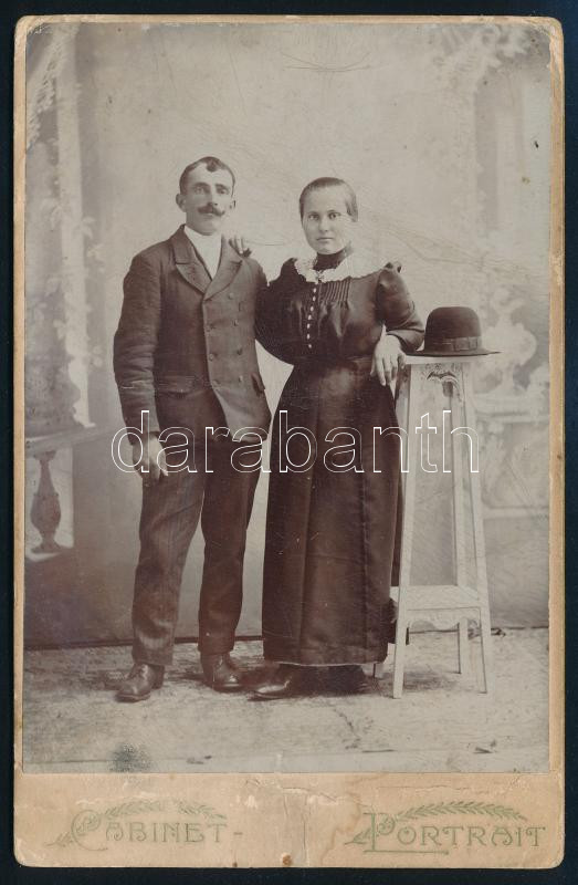 cca 1900 Házaspár műtermi fotója, keményhátú kabinetfotó, szecessziós hátlappal, viseltes állapotban, 16,5x10,5 cm