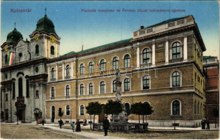 Kolozsvár, Cluj; Piaristák temploma és Ferenc József tudományos egyetem, magyar zászló. Vasúti levelezőlapárusítás 65. 1915. / church, university