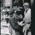 cca 1930-1940 Szendrő István (1908-2000): Postáskisasszony egy illatszerbolt eladójával az üzlet kirakata előtt, hátoldalán pecséttel jelzett fotó, 23x17 cm