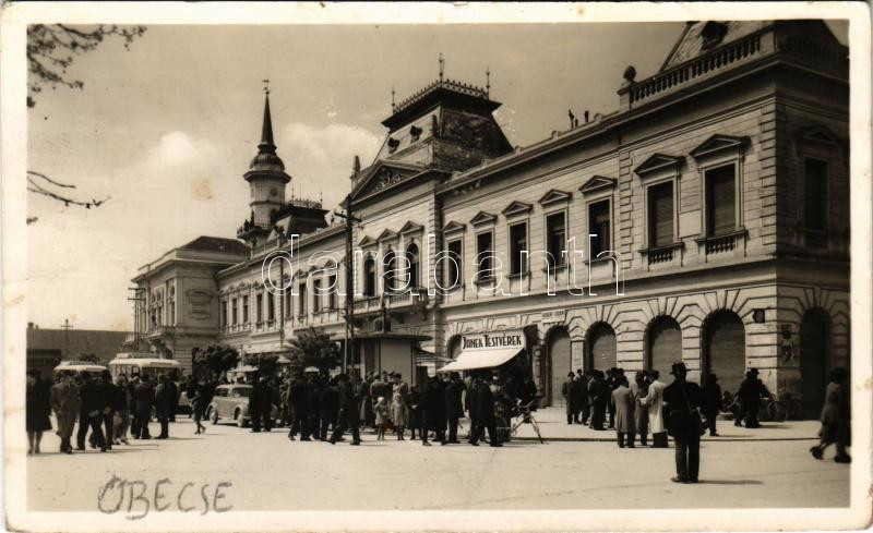 1943 Óbecse, Stari Becej; Szent István tér, Városháza, Janek Testvérek, Hubert Izidor üzlete, autóbusz, automobil, kerékpár. Ruzitska Mihály kiadása / square, town hall, shops, automobile, bicycle + '270. sz. 'Hajnal' Cserkészcsapat