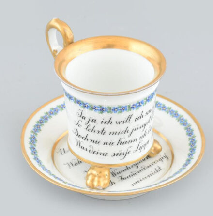 Fischer Emil porcelán emlék bögre. Kézzel festett, aranyozott porcelán, szerelmes emlék verssel németül. Oroszlántalpas bögre, alátéttel. Jelzett, kevés kopással, egyik lába ragasztott.XIX. sz. vége m: 8, d: 14 cm