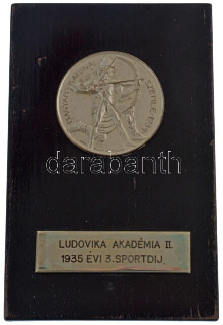 Manno Miltiadesz (1879-1935) 1934. 'Magyar Katonai Szemle' fém lemezérem fa posztamensen, gravírozott 'LUDOVIKA AKADÉMIA II. 1935. ÉVI SPORTDÍJ' lapkával (51mm) T:AU