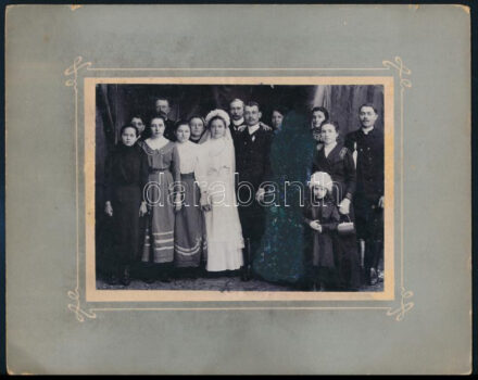 cca 1910 Esküvői csoportkép, vintage fotó jelzés nélkül, a vőlegény mellett álló nőt (anyóst?) utólag tussal letakarták, a kép hátoldalán egy matrica és felirat, amely arra utal, hogy a menyasszonyt és a vőlegényt utólag