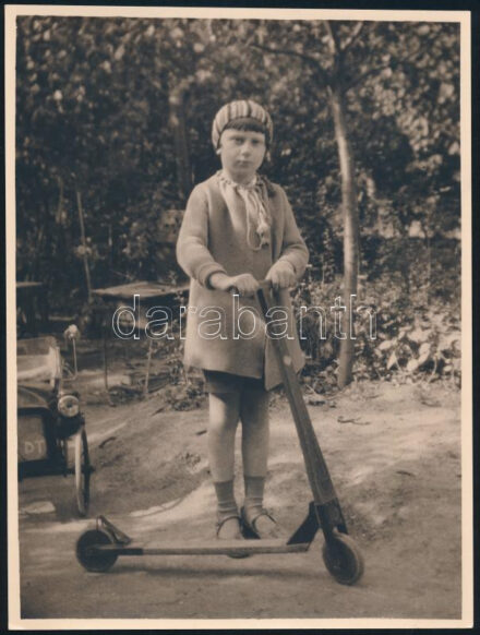 cca 1940 Kislány fa rollerrel, háta mögött gyerekautóval, fotó, 22×17 cm