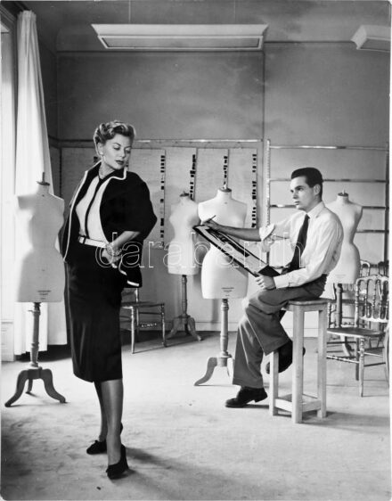 cca 1950-60 Christian Dior divatfotó, a párizsi Dior műhelyben készült, miközben egy férfi rajzolja Lénárt Angéla magyar modellt. Hátoldalán Photo Maywald, Párizs pecsétjével jelzett és Lénárt Angéla autográf feliratával. 23,5x18 cm. / cca 1950-60 Christi